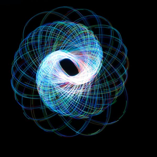 Dynamic and colorful light painting creating a spirograph-like pattern on a dark background.